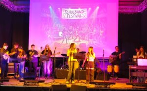 Eine Schulband musiziert auf der Bühne.